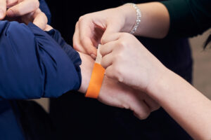 Woman putting a paper bracelet ticket on mans hand.
